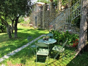 A stone building with a staircase, surrounded by a lush garden with a table and chairs. - Vacation home Chiesa by Interhome (San Polo in Chianti)