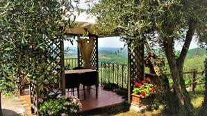 A wooden pergola with a table and chairs, surrounded by lush greenery and flowering plants. - Vacation home Chiesa by Interhome (San Polo in Chianti)