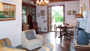 A cozy living room with a fireplace, a dining area, and a view of greenery outside. - Vacation home Chiesa by Interhome (San Polo in Chianti)
