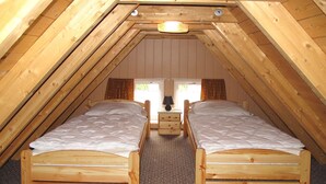 A small, cozy attic bedroom with two wooden beds, a nightstand, and a lamp. - Old Hüsung (MUZ328) by Interhome (Waren)