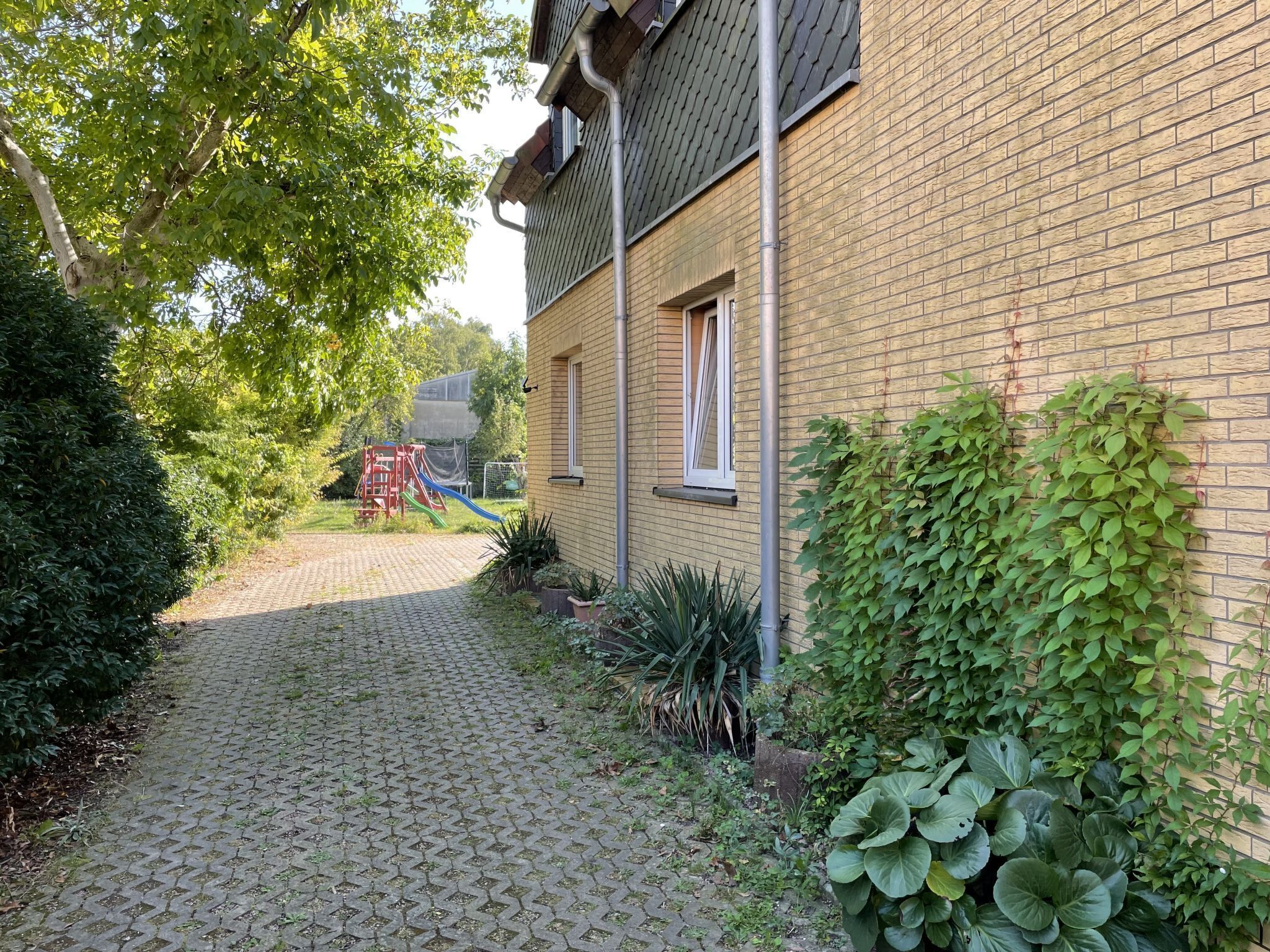 Un edificio de ladrillo con un sendero pavimentado que conduce a un parque infantil.