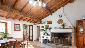 Un interior rústico con una mesa de comedor de madera, sillas, una chimenea y un sofá azul.