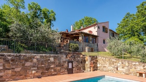 Un muro de piedra con una piscina, una escalera de piedra y un edificio con tejado rojo.