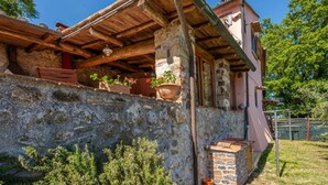 Un edificio rústico de piedra con un balcón de madera, macetas con plantas y una estructura de ladrillo.