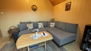 Una sala de estar acogedora con un sofá seccional gris, una mesa de centro de madera y una mesita auxiliar.
