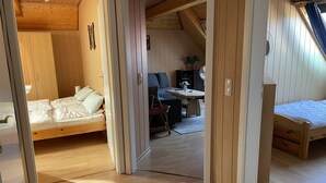 Una habitación acogedora y compacta con paredes y suelos de madera, que incluye una cama, una mesita y una silla.