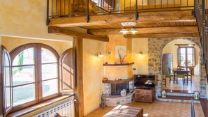 A spacious living area with a fireplace, a television, and a dining area with a table and chairs. - Villa al Sole by Interhome (Montalcino)