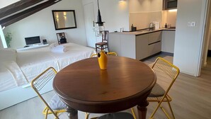 A modern kitchen with white cabinets, a dining table with yellow chairs, and a small island.