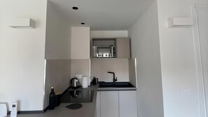 A compact kitchenette with a microwave, sink, and a small countertop area.