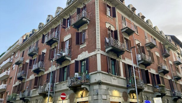 A multi-story building with balconies, a no-entry sign, and a shop at the ground level.