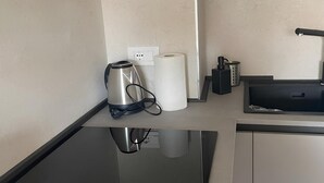 A kitchenette with a coffee maker, paper towels, and a small appliance on a countertop.