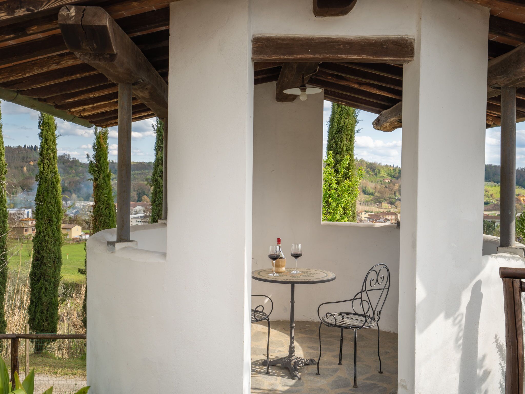 Un área de estar al aire libre techada, con una mesa y una silla, con vista a un paisaje pintoresco.