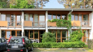 A two-story building with balconies, a car parked in front, and a well-maintained garden. - Strandvilla (LUB117) by Interhome (Ostseebad Lubmin)