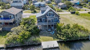 A two-story house with a dock extending into a body of water, surrounded by greenery and other residential buildings. - 3 br, dogs, canal front, sunrises/sunsets! (Avon)