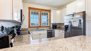 A modern kitchen with granite countertops, stainless steel appliances, and white cabinetry. - 3 br, dogs, canal front, sunrises/sunsets! (Avon)