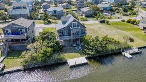 A waterfront property with a large house featuring multiple decks and a dock. - 3 br, dogs, canal front, sunrises/sunsets! (Avon)
