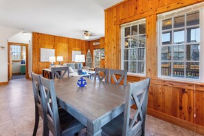 A dining area with a wooden table and chairs, a ceiling fan, and large windows with a view of the outside. - 3 br, dogs, canal front, sunrises/sunsets! (Avon)