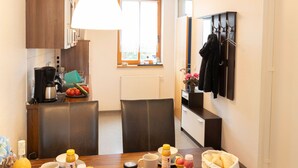 A modern kitchen with a dining area, featuring a coffee machine, fruit bowl, and various breakfast items on the table. - Strandvilla (LUB110) by Interhome (Ostseebad Lubmin)
