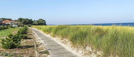 A wooden boardwalk along a beach with a clear view of the ocean.