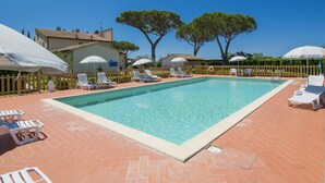 A swimming pool with lounge chairs and umbrellas, surrounded by a wooden fence and trees. - Podere Tre Termini by Interhome (Cecina)