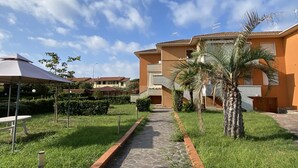 A pathway leading to a building with a tiled roof and a covered outdoor seating area. - Palazzeta III by Interhome (Vada)