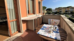 A balcony with a table set for two, a window, and a view of neighboring buildings. - Palazzeta III by Interhome (Vada)