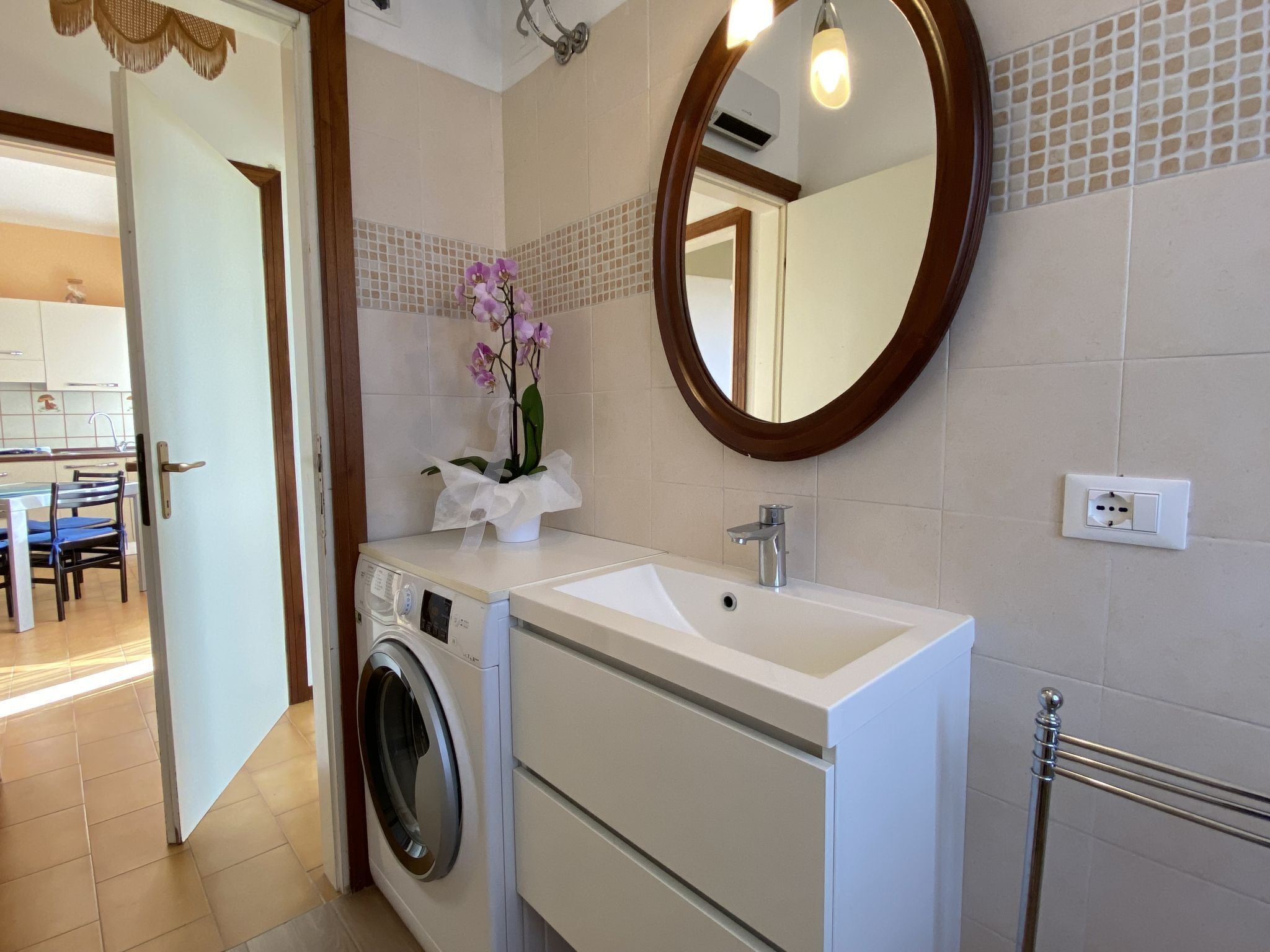 Ein modernes Badezimmer mit Waschmaschine, Waschbecken und Spiegel.