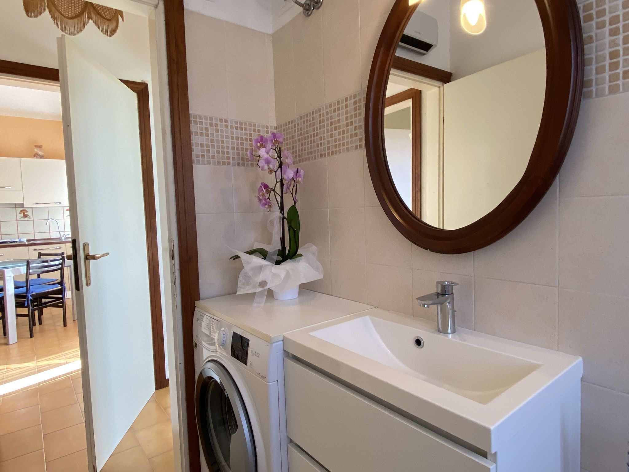 A bathroom with a washing machine, a sink, and a mirror.
