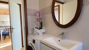 A bathroom with a washing machine, a sink, and a mirror. - Palazzeta III by Interhome (Vada)