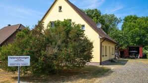 A yellow building with a satellite dish, a red garage, and a cobblestone driveway.