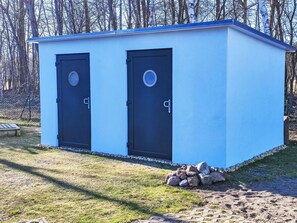 Une petite construction à un seul étage, dotée de deux portes, d’un toit plat et de fondations en pierre.