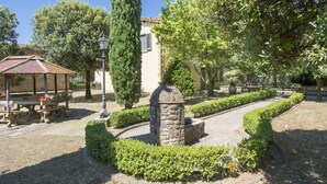 Une cour agrémentée d’une fontaine en pierre, de haies soigneusement taillées et d’un belvédère.