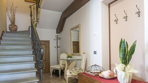 Un escalier orné de rampes en métal, une commode en bois, une table à manger avec des chaises et un miroir accroché au mur.