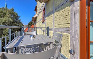 An outdoor balcony with a table and chairs, a metal railing, and a door with a handle. - Stunning apartment in Quedlinburg (Quedlinburg)