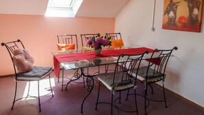 Un coin repas avec une table en verre, des chaises en métal, une nappe rouge et un luminaire suspendu.