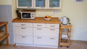 A kitchen with a microwave, a bowl of fruit, a kettle, and a small wooden cabinet. - Blechnerhof by Interhome (Feldberg)