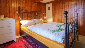 A wooden-paneled bedroom with a bed, a nightstand, a dresser, and a red patterned rug. - Blechnerhof by Interhome (Feldberg)