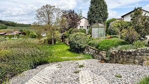A residential area with a stone wall, a paved pathway, and a small glass greenhouse. - Am Weinberg by Interhome (Bad Dürkheim)