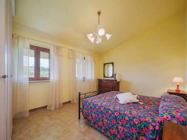 Une chambre avec deux lits, une fenêtre avec des rideaux, une commode, un miroir et un luminaire au plafond.