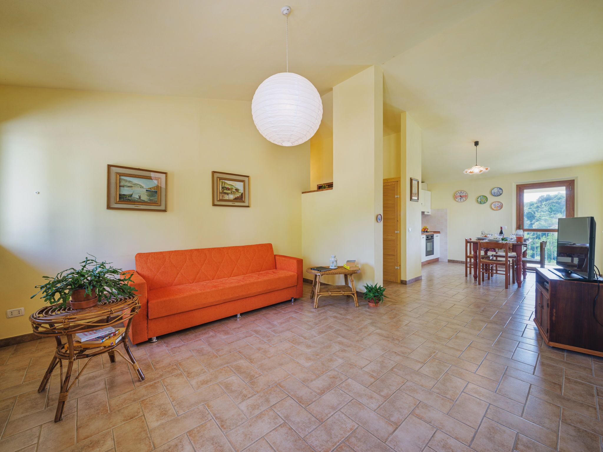 A living room with a sofa, a dining table, and a kitchen area.