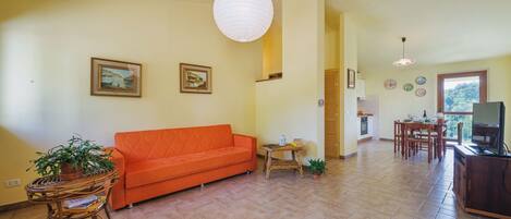 A living room with a sofa, a dining table, and a kitchen area.