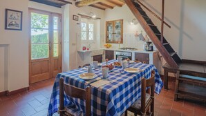 Une cuisine rustique avec une nappe à carreaux, des poutres en bois et un escalier.