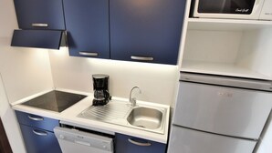 A compact kitchen with a built-in dishwasher, a coffee maker, and a microwave. - Apartment Alba by Interhome (Lido di Spina)