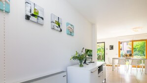 Una cocina moderna con armarios blancos, una isla central con un florero y un comedor con mesa y sillas.