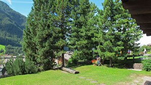 A garden with a stone pathway, a wooden bench, and a large tree. - Apartment Tirol by Interhome (Ortisei St Ulrich)