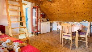 Un interior de fusta acollidor amb un llit d'altitud, una zona de menjador i una cuina.