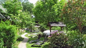 Jardí amb camí pavimentat, seients de relaxació i una glorieta.