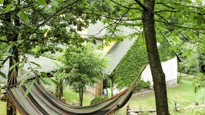 Una cadira espanyola en un jardí frondós amb arbres i una casa al fons.