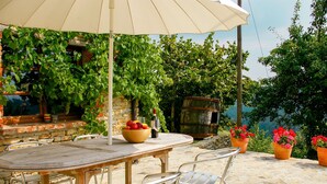 Un espacio de comedor al aire libre con una mesa, sillas y una sombrilla.