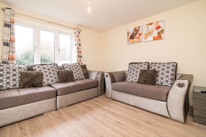 A modern living room with a sectional sofa, a small table, and abstract wall art.